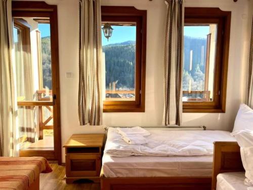 een slaapkamer met twee bedden en twee ramen bij Vila Martina in Smilyan