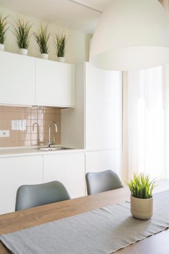 a kitchen with white cabinets and a table with chairs at Appartamenti 2 in Dervio