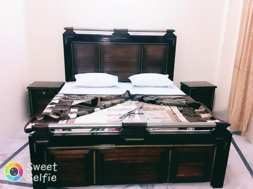 a bed in a room with a wooden frame at New Grand Hotel in Dargai