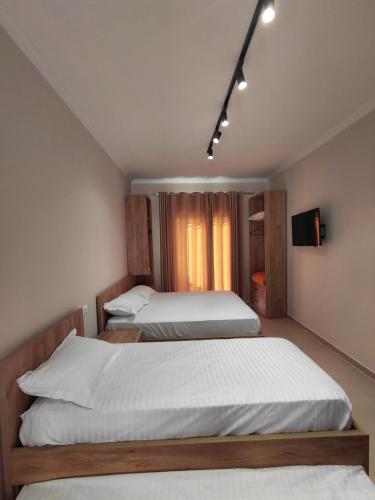a bedroom with two beds and a tv on the wall at Hotel Lalez Durres in Durrës