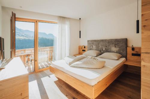 a bedroom with a large bed and a large window at Oberegghof Ferienwohnung Ifinger in Rifiano