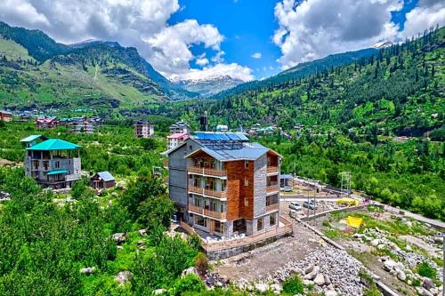 a building on a hill with mountains in the background at Mystic Manali in Palchān