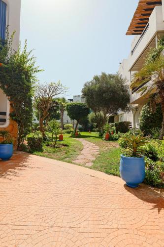 a brick walkway with blue pots in a yard at Lagoon Garden - 2 chambres proche Plage avec Piscine in Skhirat