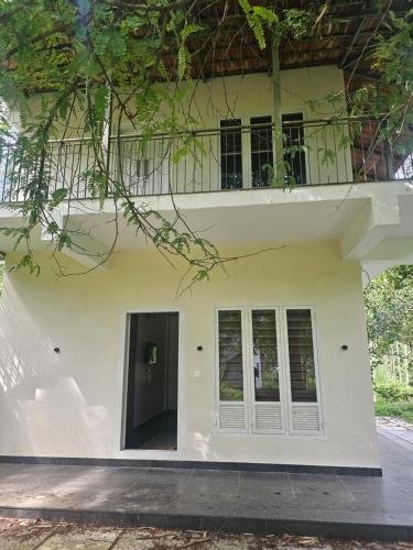 a white building with a balcony on top of it at Hamai Grand Home Stay in Ambalavayal