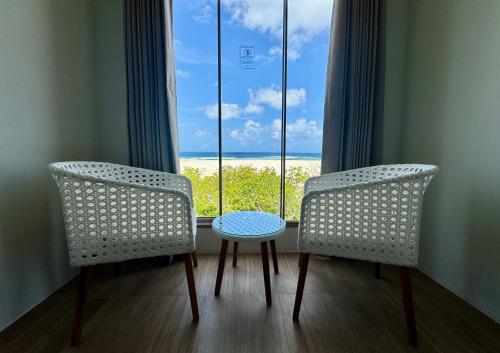 two chairs and a table in front of a window at Avyanna Gulhi Beach Hotel in Gulhi