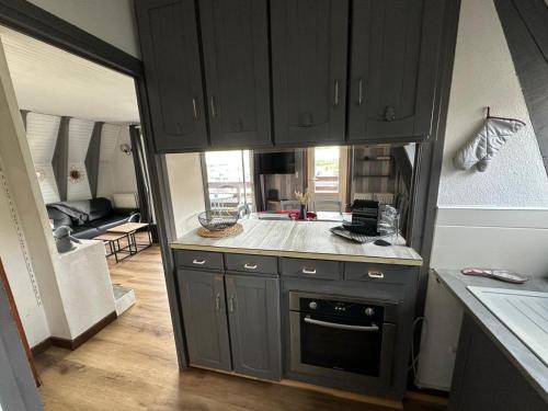 a kitchen with black cabinets and a living room at Le Delta de Super-Besse in Super Besse