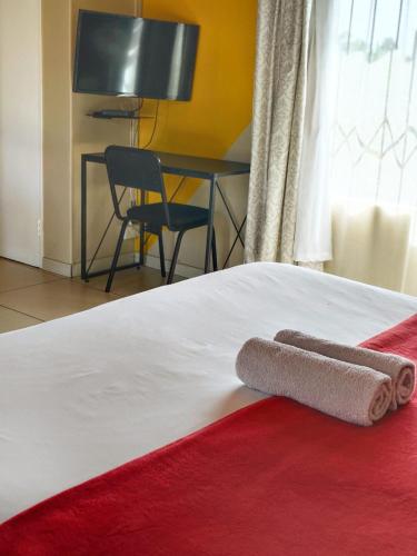 a bed with two towels sitting on top of it at Tokelo Guesthouse Emalahleni in Witbank