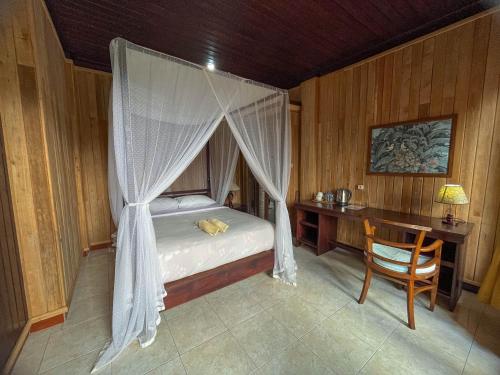 a bedroom with a canopy bed and a desk at Puri Alam Bali in Munduk