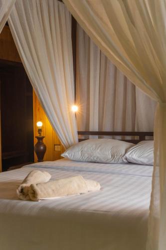 a bed with a towel on it with a curtain at Puri Alam Bali in Munduk