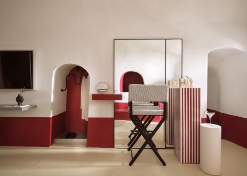 a room with a chair and a table with a mirror at Neema Maison Finikia Santorini in Oia