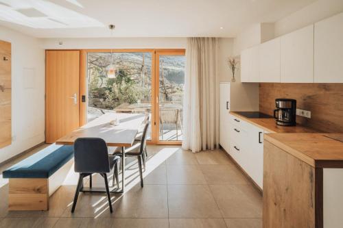 a kitchen with white cabinets and a table and chairs at Oberegghof Ferienwohnung Garten in Rifiano
