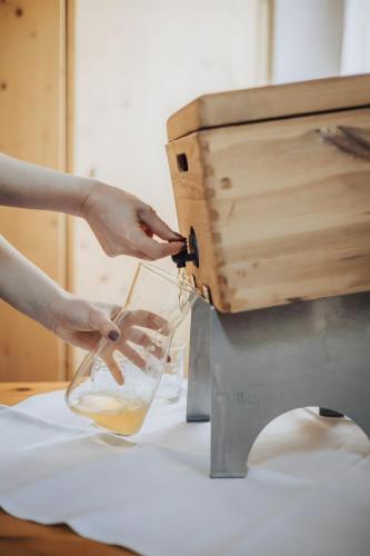 a person pouring liquid into a glass in a machine at Oberegghof Ferienwohnung Ifinger in Rifiano