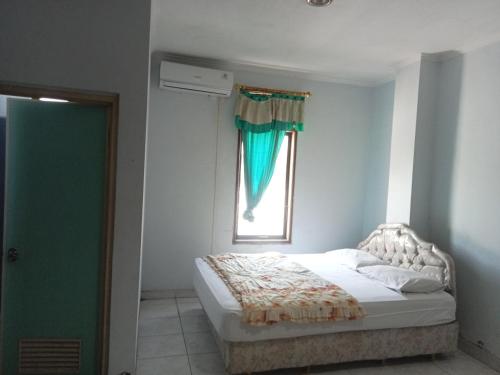 a white bedroom with a bed and a window at Hotel Taman Rai in Tabanan