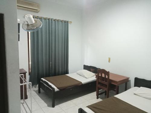 a room with two beds and a table and a chair at Hotel Taman Rai in Tabanan