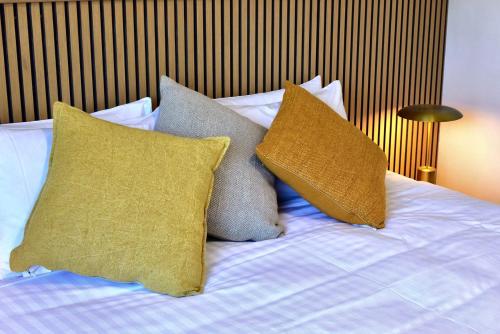 a bed with four pillows on top of it at Lufra Beachside Hotel in Eaglehawk Neck