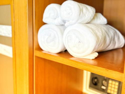 a pile of white towels on a shelf at Swimming Pool Apartment Hotel in Patong Beach