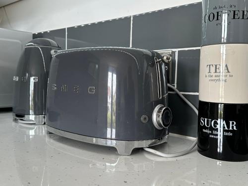 a toaster and two bottles of wine on a counter at Driftwood at BotanyBay - Dogs Welcome in Broadstairs