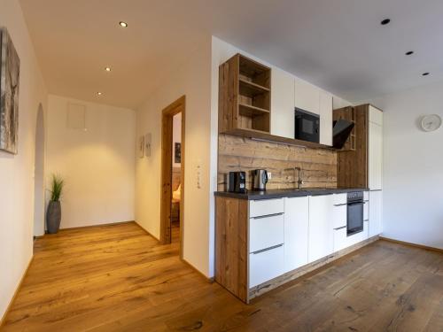 a kitchen with white cabinets and a wooden floor at Apartment in Neustift in a quiet location in Neustift im Stubaital