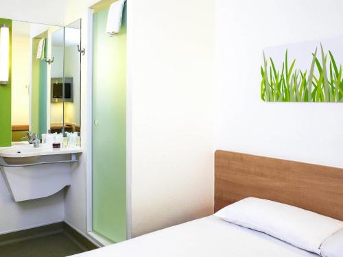 a bedroom with a bed and a sink and a mirror at ibis budget Birmingham Airport Terminal Building - NEC in Bickenhill