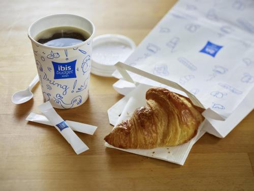 a table with a cup of coffee and a croissant at ibis budget Birmingham Airport Terminal Building - NEC in Bickenhill