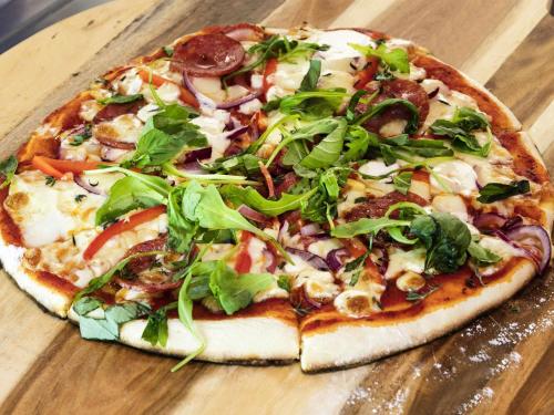 a pizza sitting on top of a wooden table at ibis budget Birmingham Airport Terminal Building - NEC in Bickenhill