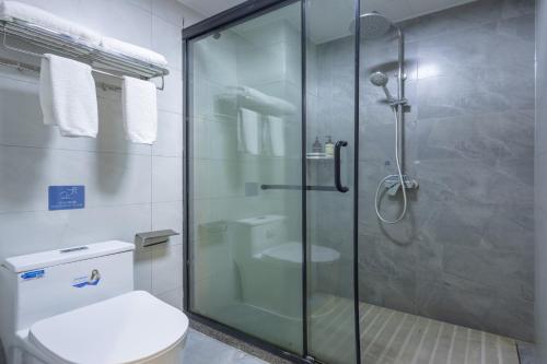 a bathroom with a glass shower with a toilet at 铂曼智慧酒店-张家界国家森林公园门票站店 in Zhangjiajie