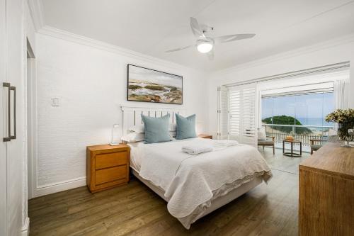a white bedroom with a bed and a window at Ocean Whisper At 42 in Gqeberha