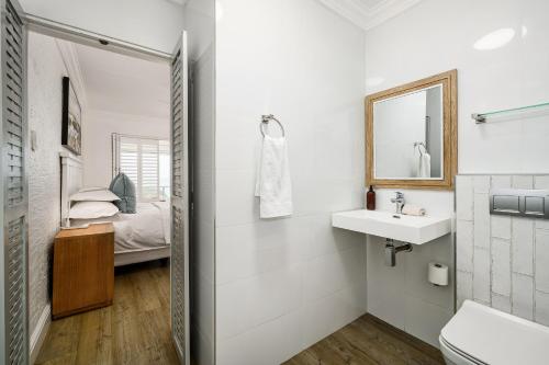 a white bathroom with a sink and a mirror at Ocean Whisper At 42 in Gqeberha