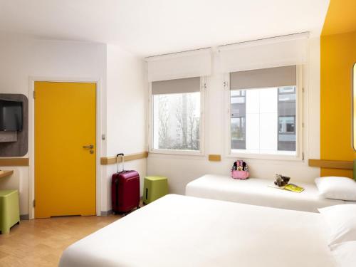 a bedroom with two beds and a yellow door at ibis budget Warszawa Centrum in Warsaw