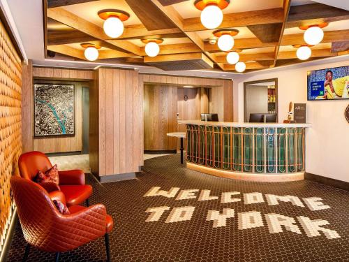 a lobby with a library with a red chair and a library at ibis Styles York Centre in York