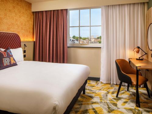 a hotel room with a bed and a desk and a window at ibis Styles York Centre in York