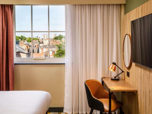 a room with a bed and a desk and a window at ibis Styles York Centre in York