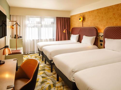 a hotel room with three beds and a desk at ibis Styles York Centre in York