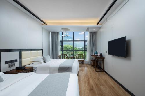 a hotel room with two beds and a flat screen tv at 铂曼智慧酒店-张家界国家森林公园门票站店 in Zhangjiajie
