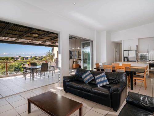 a living room with a black leather couch and a table at The Sebel Twin Waters in Twin Waters