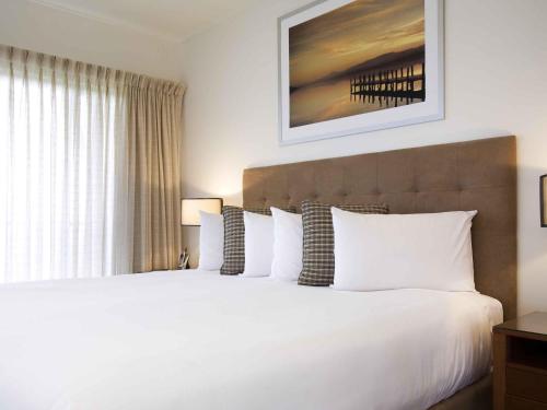 a bedroom with a large bed with white pillows at The Sebel Twin Waters in Twin Waters