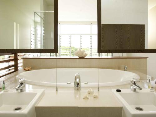 a bathroom with two sinks and a large tub at The Sebel Twin Waters in Twin Waters