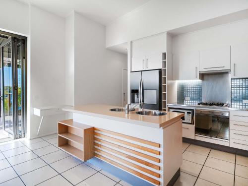 a kitchen with white cabinets and a counter with a sink at The Sebel Twin Waters in Twin Waters