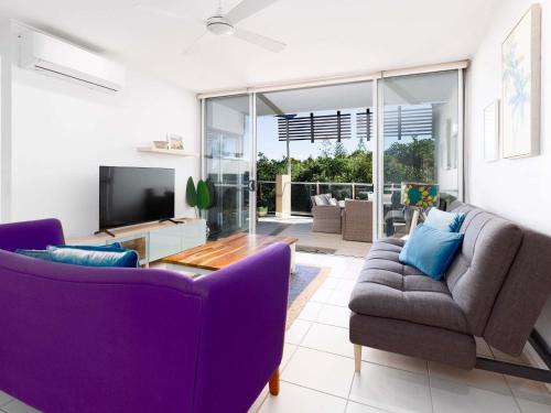 a living room with a purple couch and a tv at The Sebel Twin Waters in Twin Waters
