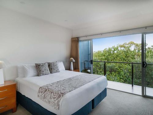 a bedroom with a bed and a large window at The Sebel Twin Waters in Twin Waters