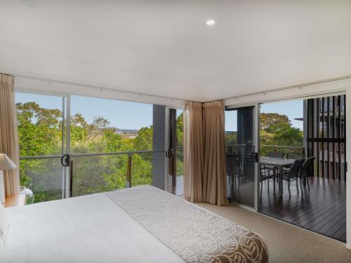 a bedroom with a bed and a balcony with a table at The Sebel Twin Waters in Twin Waters