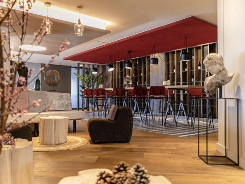 a lobby with a bar with red stools at Mercure Valence in Valence