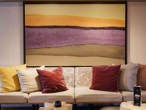 a couch with colorful pillows in front of a painting at Mercure Valence in Valence