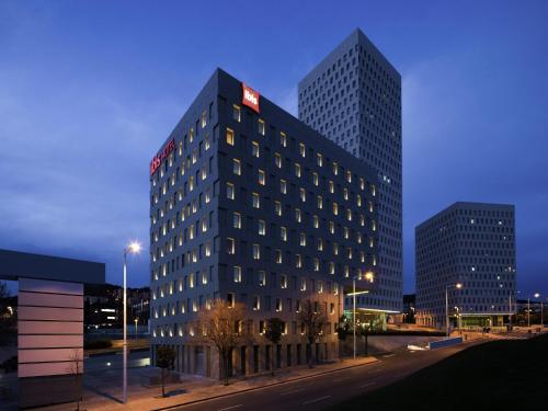 a tall building with a sign on the top of it at Ibis Barcelona Santa Coloma in Santa Coloma