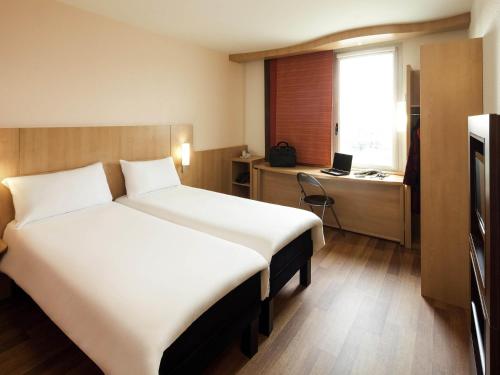 a hotel room with a large bed and a desk at Ibis Barcelona Santa Coloma in Santa Coloma