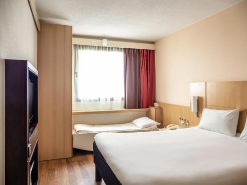 a hotel room with two beds and a window at Ibis Barcelona Santa Coloma in Santa Coloma