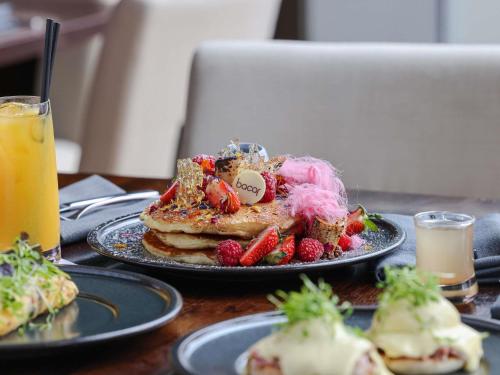 a table with a plate of food with strawberries and pancakes at Pullman Sydney Olympic Park in Sydney