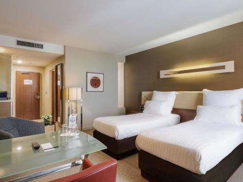 a hotel room with two beds and a table at Pullman Sydney Olympic Park in Sydney