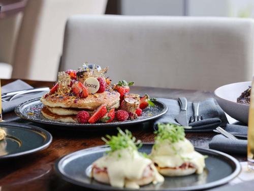 a table with a plate of food with strawberries and pancakes at Pullman Sydney Olympic Park in Sydney