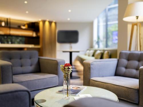 a room with couches and a vase of flowers on a table at Pullman Sydney Olympic Park in Sydney